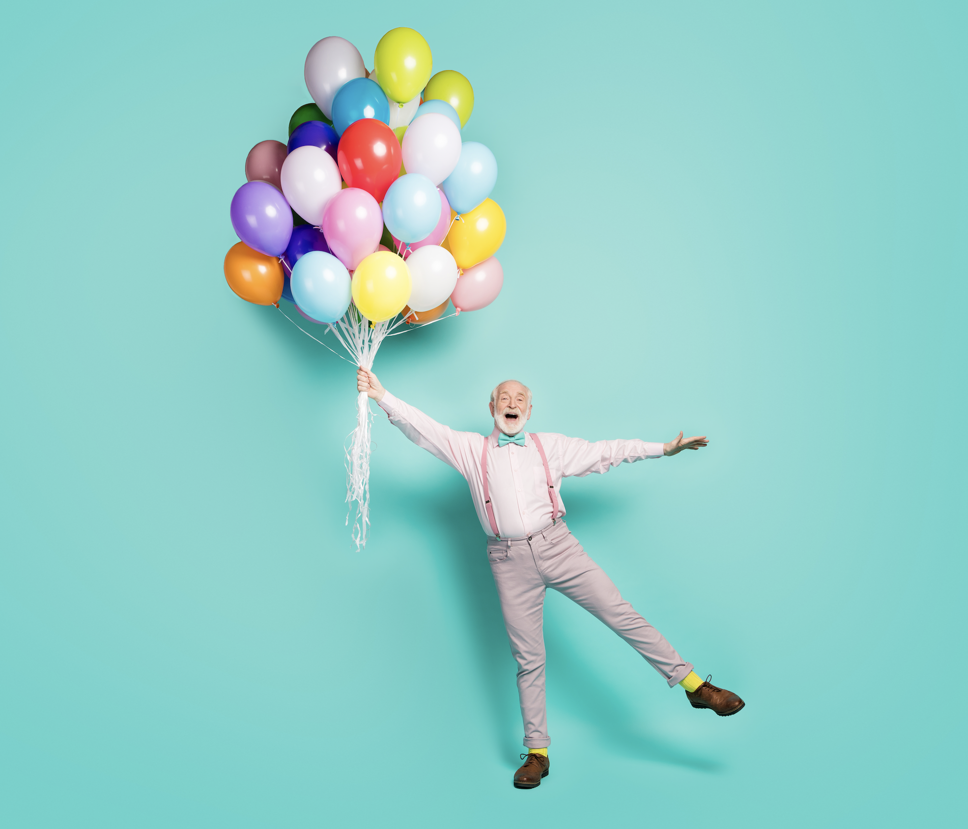 Homme souriant suspendu à des ballons multicolores – symbole de communauté joyeuse et d'apprentissage ludique chez DISC Know Futures